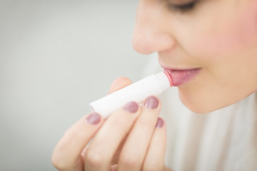 girl applying lip balm to protect from winter. image source-pixabay